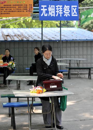 4月2日,一位市民在广州市火葬场无烟拜祭区擦拭逝者的骨灰盒.