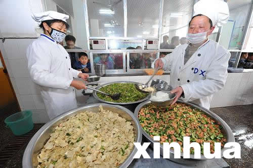 4月3日,湖北省保康县店垭镇小学食堂厨师在为学生盛饭.