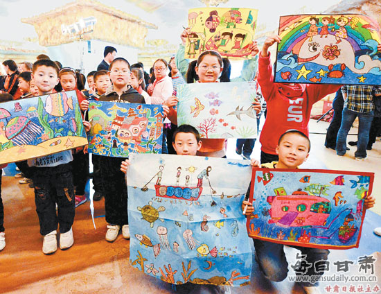 首届"爱海洋·爱环保"儿童书画大赛获奖者展示自己的绘画作品(图)