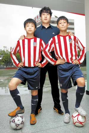 深圳南山育才小学学生叶志威（左）与容琳朝被西甲马德里竞技球队看中。图为两名小球员与教练合影。 　　吴邦/摄