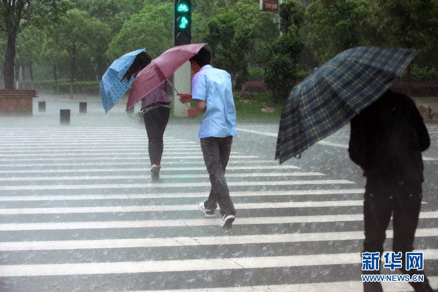 4月24日上午,江西南昌市民在街头冒着风雨前行.新华社记者周密摄