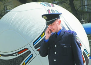4月28日，一名警察在乌克兰第聂伯罗彼得罗夫斯克市从欧锦赛官方比赛用球“探戈12”的模型旁走过。