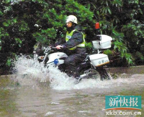 交警骑着摩托车趟水赶赴水浸点。郑迅/摄