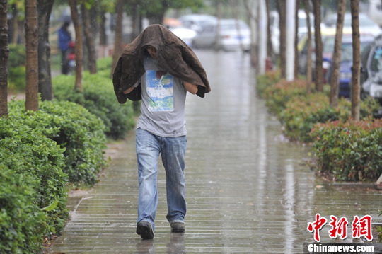 图为5月8日,昆明街头撑起衣服挡雨的市民.中新社发 刘冉阳 摄