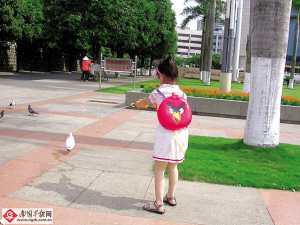 5月11日,在南宁市民族广场,一名小女孩背着愤怒小鸟样式的水枪在广场