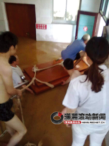 ( 余坪乡中心卫生院，村民与护士用木板转移病人。 图/潇湘晨报读者提供)
