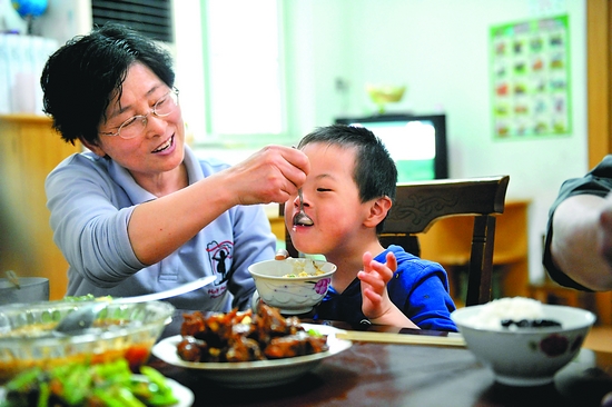 "妈妈"在照顾孤残儿童的饮食.