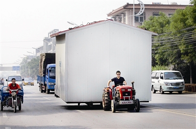 "昨天,记者看到一辆拖拉机载着刚做好的活动板房走在宋庄小堡的马路上