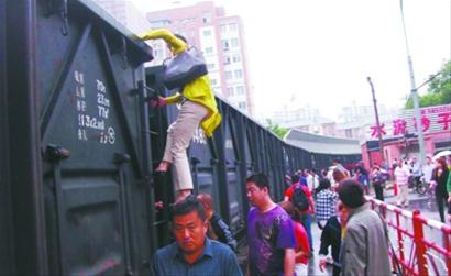 趴窝火车拦腰截断路 部分市民冒险徒手攀越火车(图)