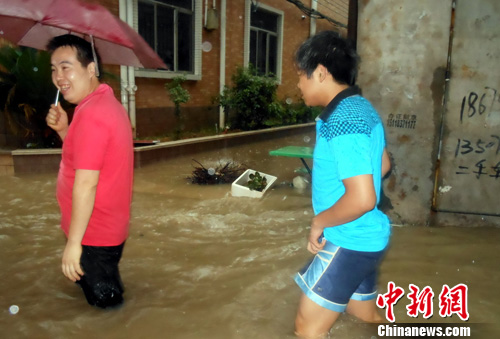 6月22日，行人从积水严重的江西遂川县城一处低洼路段涉水回家。李建平 摄