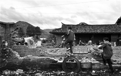 昨日，云南省永宁乡上开基村村民翻越坍塌的院墙。本版图片/新华社记者 陈海宁