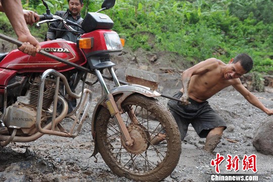 村民用钢筋协助摩托车“过河”。 张浪 摄