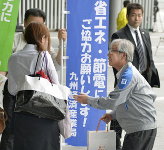 日本九州地区7月2日实施夏季节电，九州电力社长瓜生道明（右）在福冈市JR博多站前分发传单，呼吁配合节电。