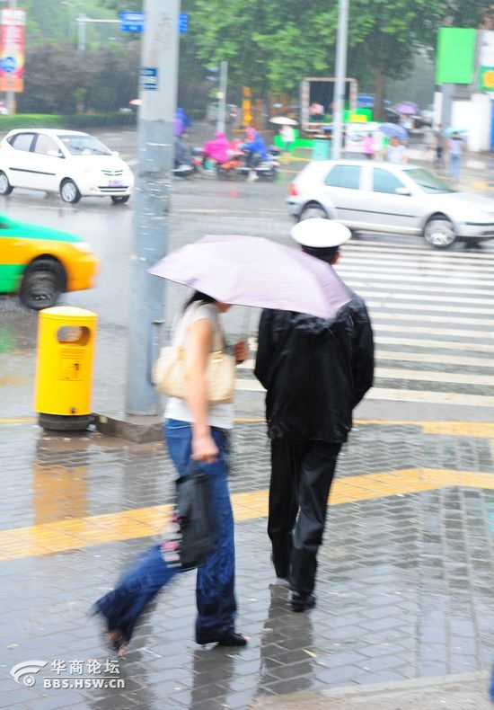 这位全身淋湿的交警拧干衣服上的雨水,倒掉了鞋子里的水.