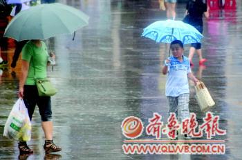 一名小朋友撑伞在雨中奔跑. 张晓鹏 摄