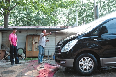 大庄在洗车，小田在一旁看，学习业务。