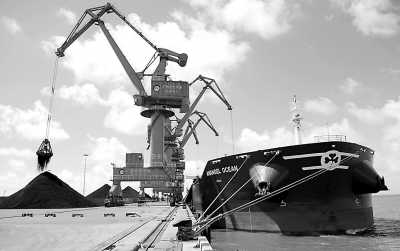 图为一艘外籍远洋货轮在广西钦州保税港区码头下卸锰矿石。