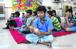 17岁的流浪儿拉姆星(前)在流浪儿童收容所点算一天的收入,之后他把钱存入“儿童发展宝箱”账户,希望有朝一日能够凭着这些存款自己当老板。
