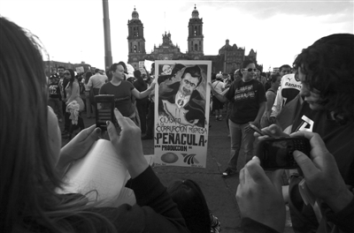 7月7日，墨西哥城的佐卡罗广场，示威者举着总统大选获胜的革命制度党成员培尼亚・涅托的涂鸦画像。