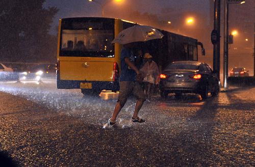 7月10日，在珠市口附近，行人冒雨出行。当日，北京遭遇强降雨。北京市气象台当天傍晚先后发布雷电黄色预警和暴雨蓝色预警，提醒市民注意防范。新华社记者 李文 摄