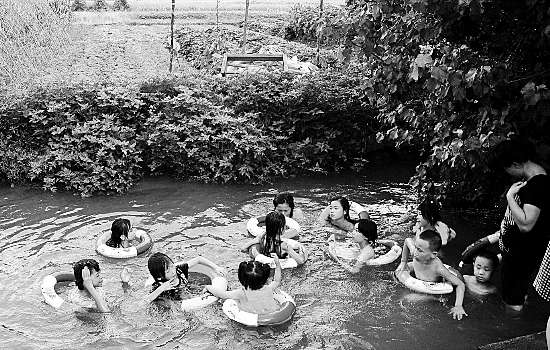 经过屋后,农村的孩子们在家长的带领下来到自家的门口戏水游泳消暑