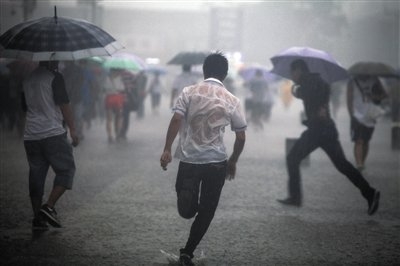 昨日,北京火车站广场,正在雨中奔跑的人们.侯少卿 摄