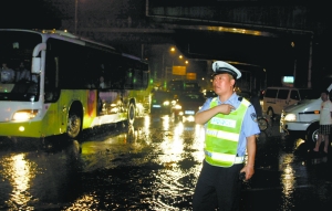 昨天晚上，本市多个路段因积水车辆难行，交警在雨中指挥疏导交通。 本报特约摄影 石硕