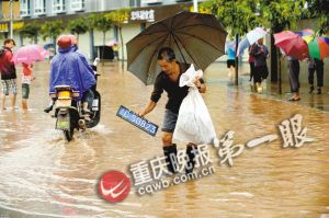 荣昌县吴家镇双流村街道变成泽国,一位村民在水中捞出车牌.图片