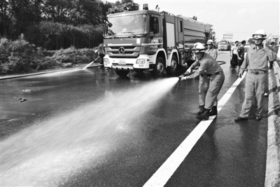 消防人员对退水和清理过淤泥的路面进行清洗。