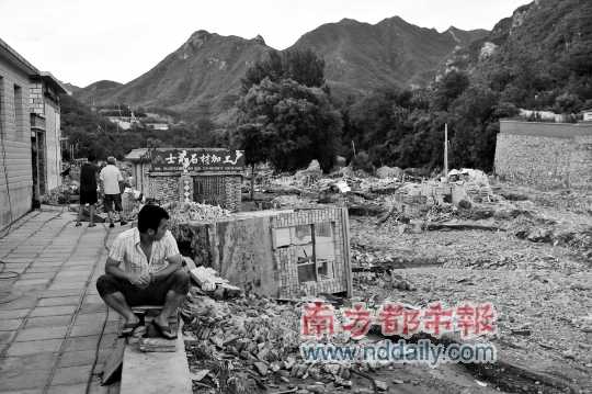 前日，北京市房山区河北镇檀木港村，村民坐在废墟上，背后是被整体推倒的房屋。C FP供图