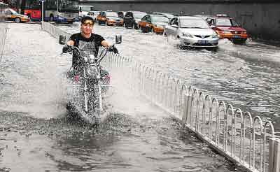 7月21日下午，在北京东城区的广渠门桥附近，一辆摩托车从积水的路面驶过。