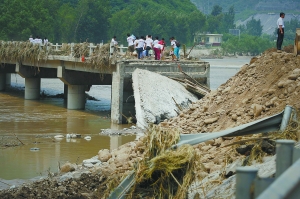 十七渡大桥被洪水冲垮，通往野三坡的道路在此完全中断，一些90后志愿者徒步过河为当地留守的人送食物和饮用水。 李刚摄