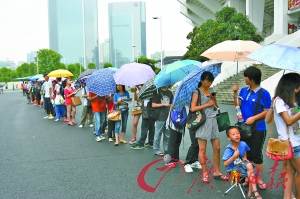 球迷在雨中排队购票，队伍几乎绕了体育场一整圈。