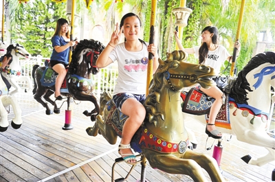 7月27日,参加活动的一名小女孩在骑木马.