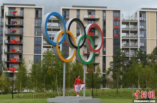 当地时间8月4日，伦敦奥运村内的巨型五环前，众多运动员合影留念。中新网记者 陈静 摄