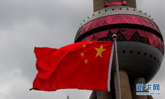8月7日拍摄的上海东方明珠塔下，国旗在强劲的风中飘扬。