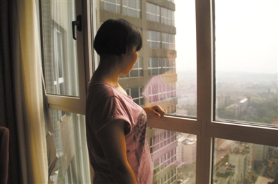 唐慧站在宾馆的落地窗前，她不愿面对镜头。她希望事情过去后，家庭的伤痛能平复，一家人能安安静静地生活下去。