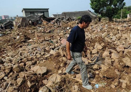 8月11日，岱山县长涂镇沈家坑村村民经过一处因水库坍塌造成的废墟。新华社记者 崔新钰 摄