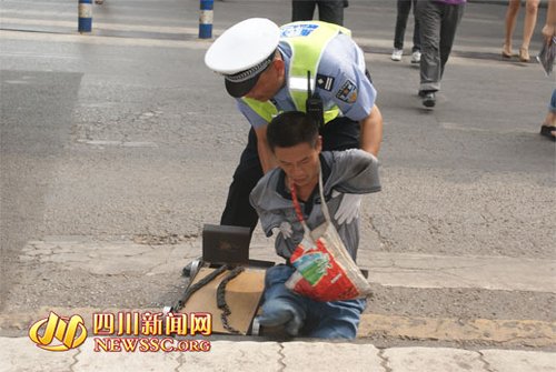 75米的交警邓拥军弯下身子扶助一名四肢残疾的乞丐过人行横道.