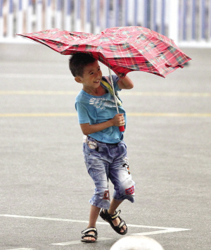 8月17日下午5时,南宁市百货大楼门前,一名小朋友的雨伞被大风吹变形