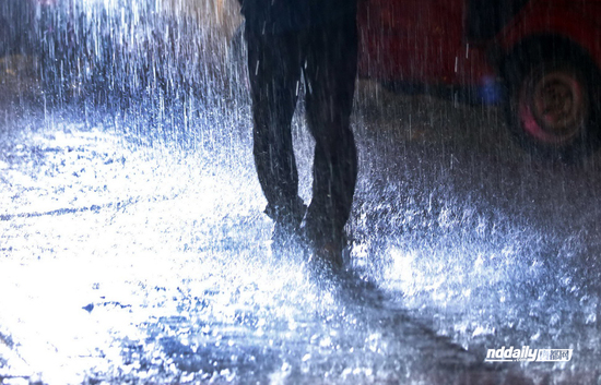 佛山祖庙路百花广场前,一名男子走在雨中,密集的雨珠从他身边纷纷落下