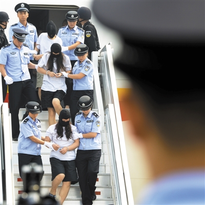昨日，在北京首都国际机场，涉案犯罪嫌疑人被押解下飞机。新华社记者 戚恒 摄