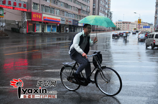 上午10点,乌市新民路一个路人没有带伞,将报纸顶在头上挡雨.