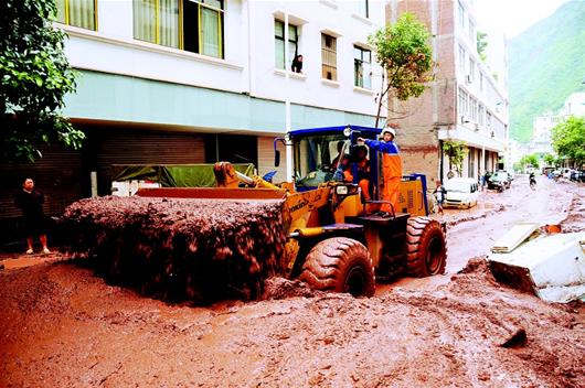 湖北日报讯 图为:11日,救灾人员驾驶铲土机在云南彝良县城疏通道路.