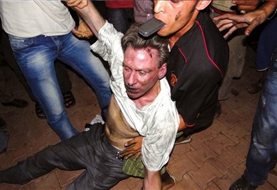 9月11日，班加西街头，几名利比亚平民正在帮助一名失去意识的男子，目击者称该名男子是史蒂文斯。图/东方IC