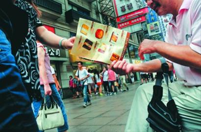 南京东路上，不少“黄牛”拿着月饼广告向路人招揽生意。