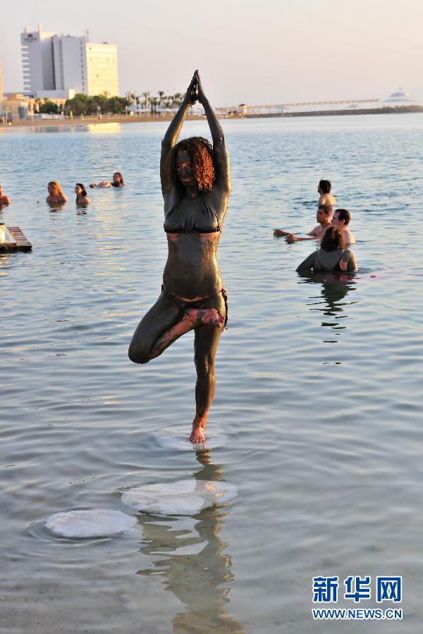 参加集体漂浮活动的一名女子站在死海盐花上练