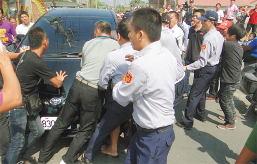 抗议群众与数名黑衣人围攻县长座车，警方隔开群众。台湾《联合报》
