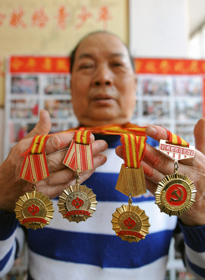 王金明展示他这些年来获得的奖章（10月26日摄）。新华社记者 李博 摄