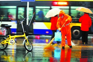 昨天，长安街上的环卫工人在寒风和雨水中清扫路面。本报记者 戴冰摄